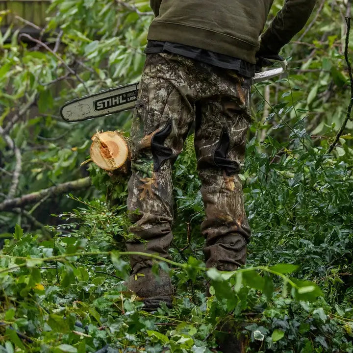 Tree surgeon wearing Breatheflex Pro Realtree chainsaw trousers while using a chainsaw in an outdoor setting.