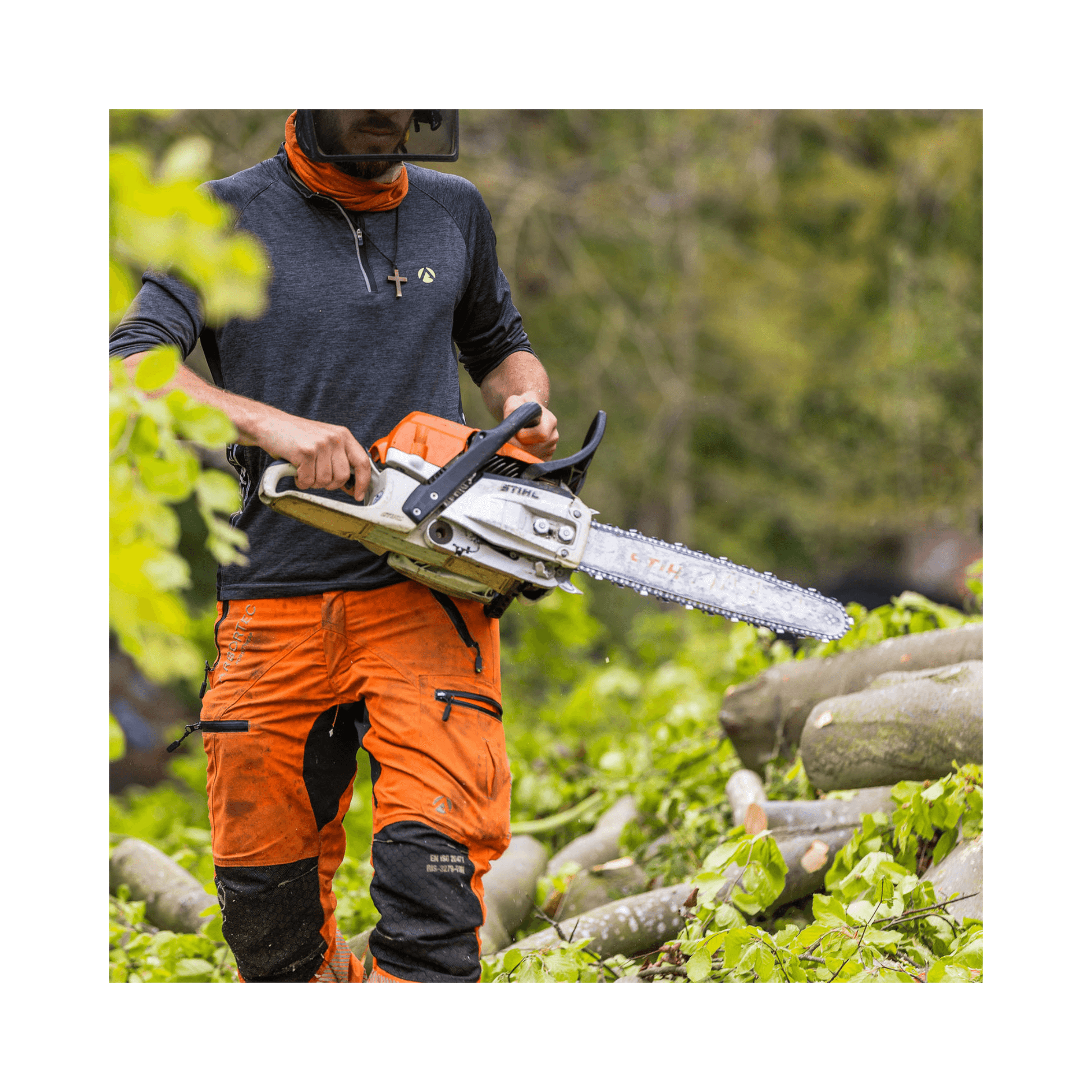 Tree surgeon wearing Arbortec Breatheflex Pro chainsaw trousers in Hi-Viz orange, using a chainsaw in a wooded area.