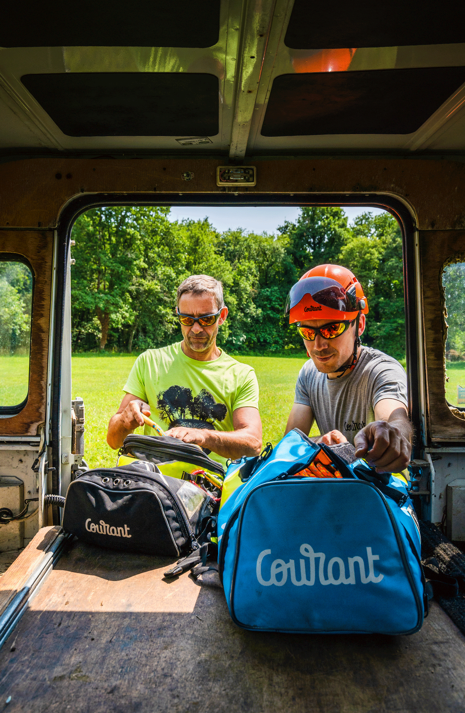 Two tree surgeons packing gear from Courant climbing bags in a vehicle, ready for outdoor work.