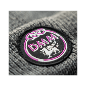 Close-up of the DMM logo on the Heritage Beanie in grey, featuring a pink emblem and craftsmanship for tree surgeons.