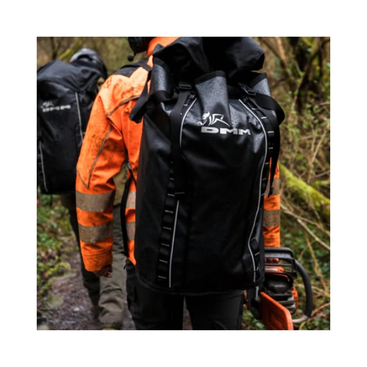 DMM Porter Rope Bag worn by professionals on a rainy outdoor trail, showcasing its durability and high-capacity design.