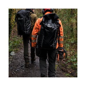 Two professionals carrying DMM Porter Rope Bags and a chainsaw on a wooded trail.
