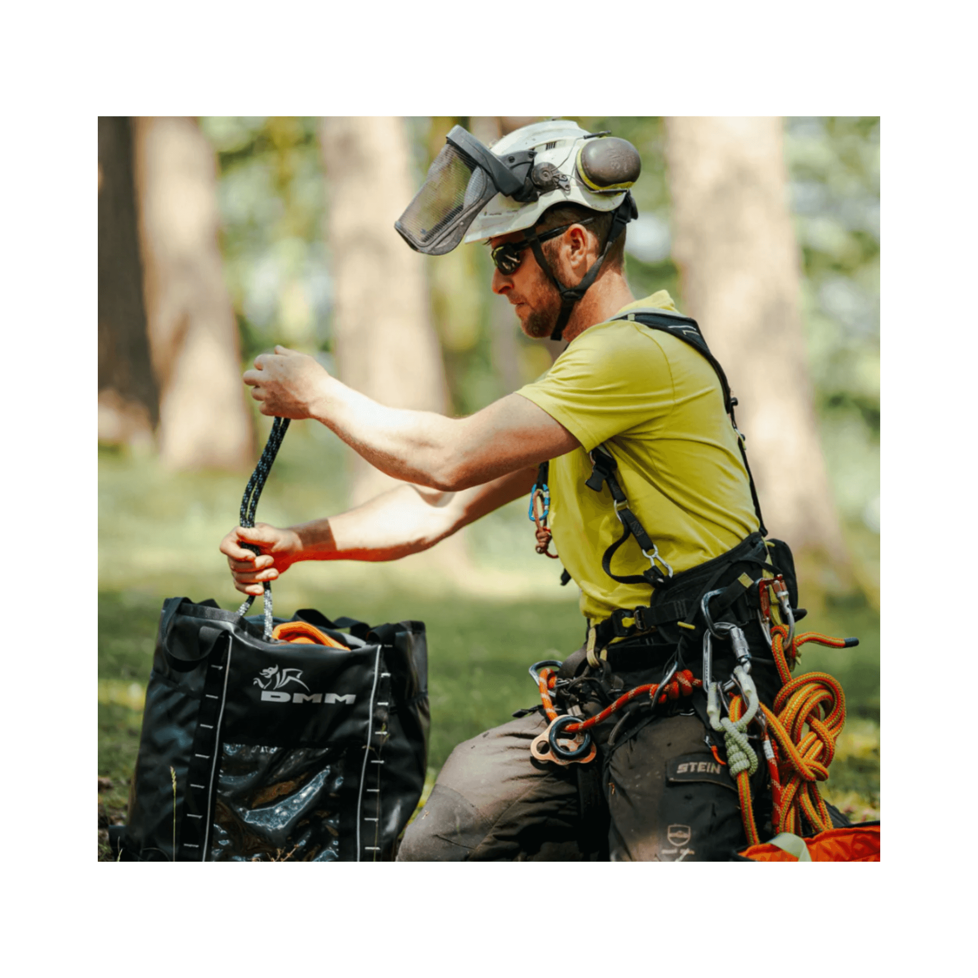 A tree surgeon using a DMM Transit Climbing Rope Bag to manage climbing gear in a forest setting.