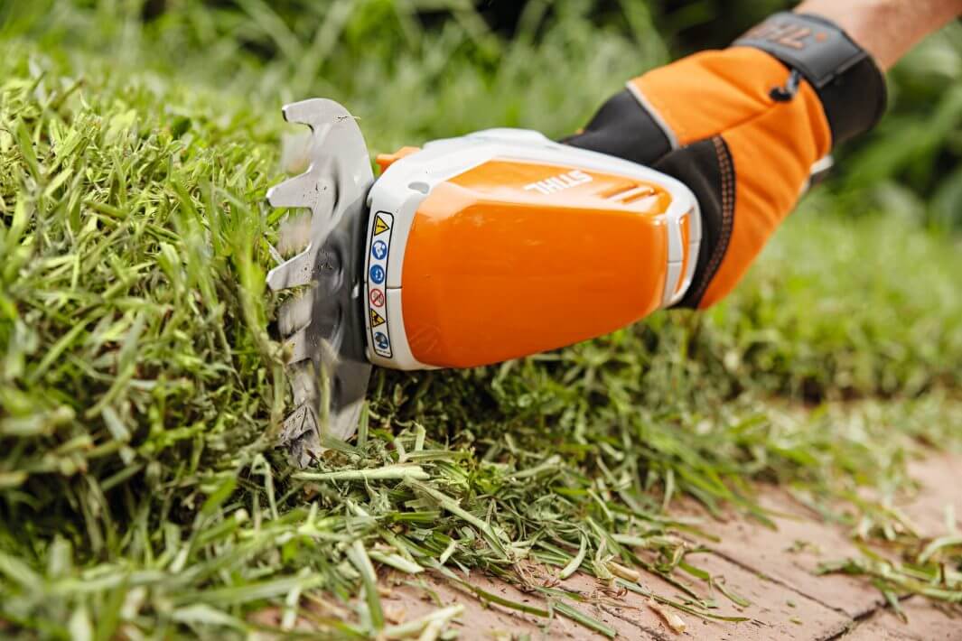 STIHL HSA 26 cordless shrub shears in use for precise grass trimming, perfect for tree surgeon tasks and garden maintenance.