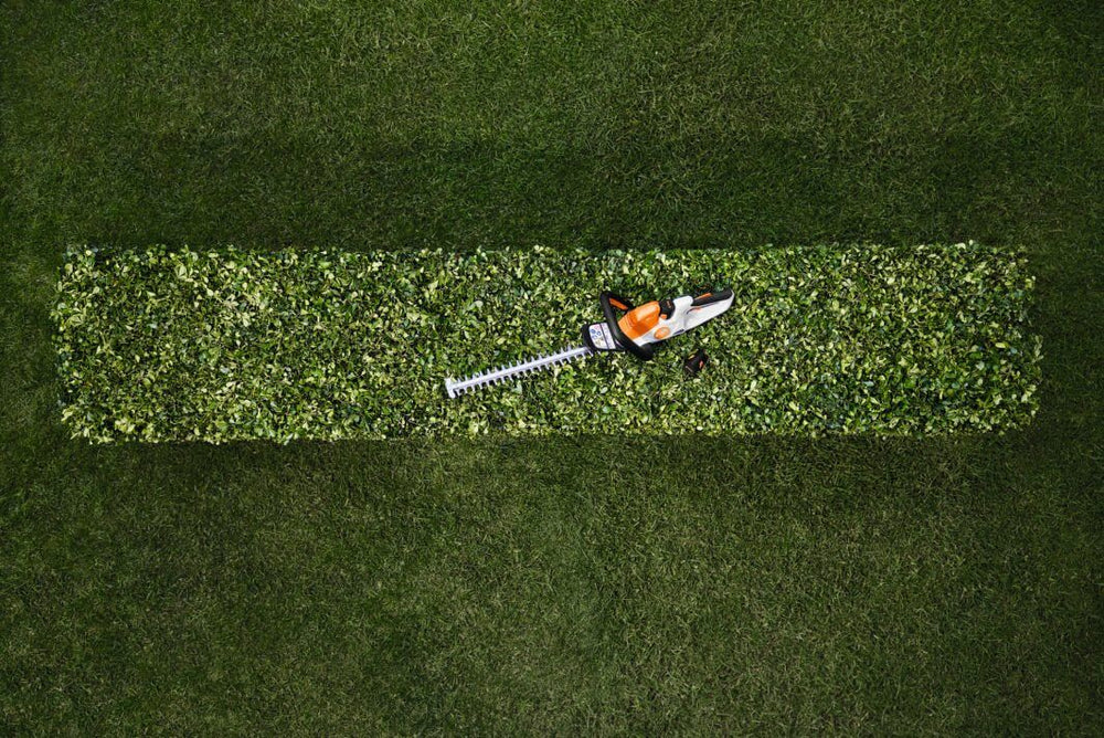 HSA 40 cordless hedge trimmer resting on neatly trimmed hedge, showcasing its lightweight design for tree surgeons.