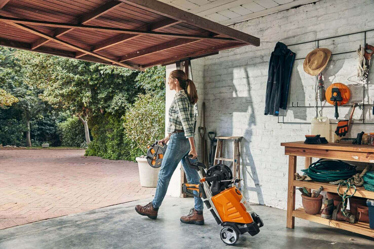 Person carrying garden tools in a garage, showcasing DIY home improvement and outdoor maintenance.