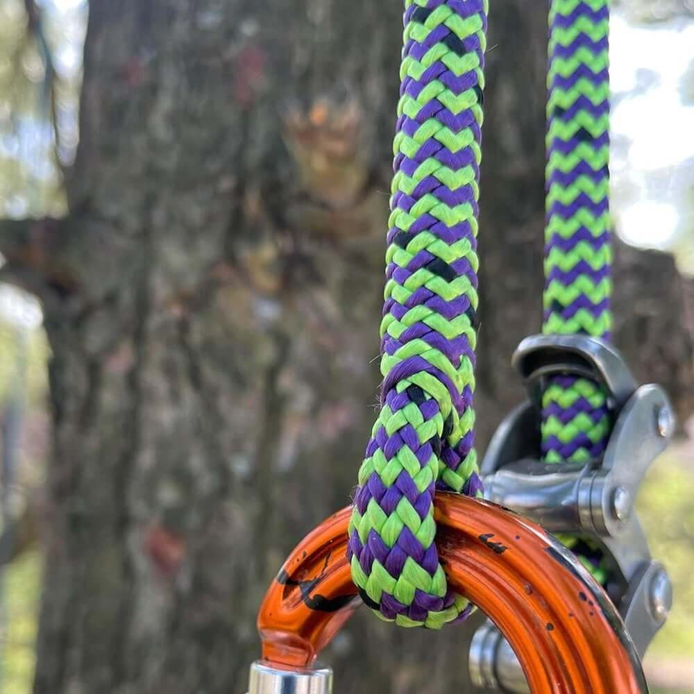 Close-up of Vesper Climbing Line 11.8mm in vibrant green and purple, attached to climbing gear for tree surgeons.