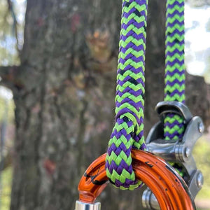 Close-up of Vesper Climbing Line 11.8mm in vibrant green and purple, attached to climbing gear for tree surgeons.