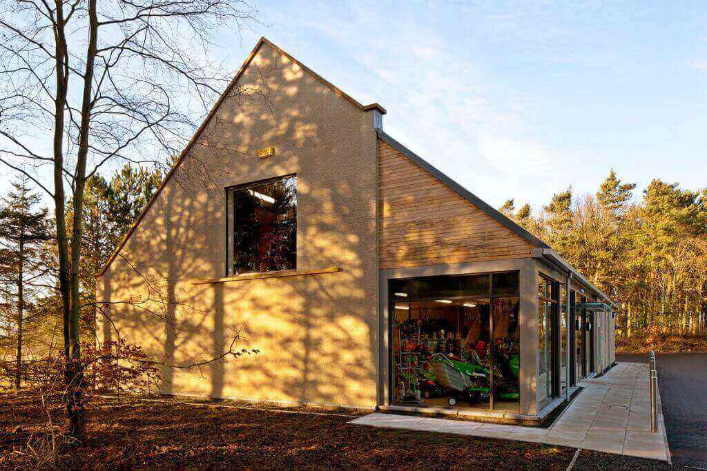 Modern building with large windows and a wooden facade, surrounded by trees, suitable for a tree surgeon's workspace.