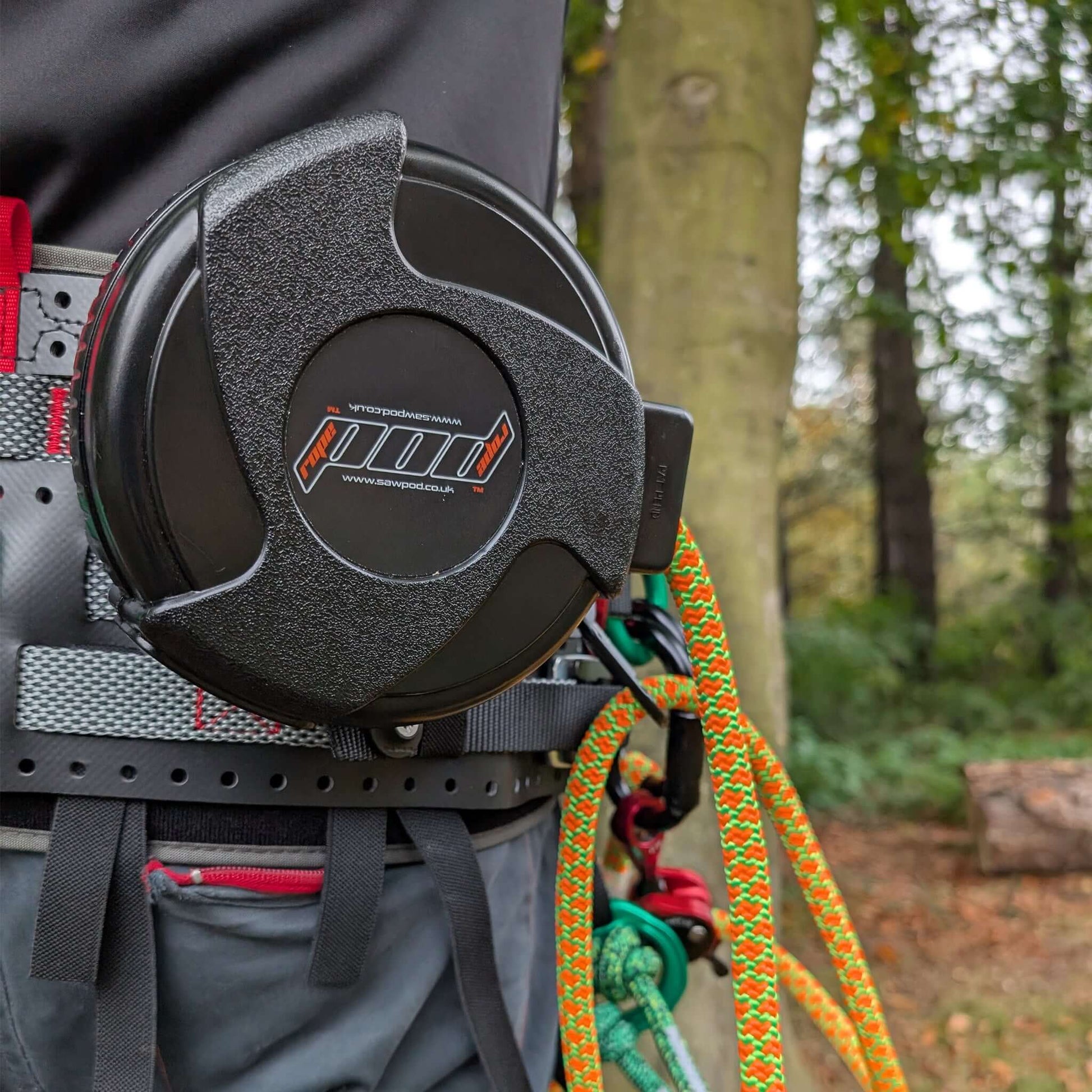 RopePod Retractable Lanyard System attached to a harness with colorful ropes in a wooded setting.