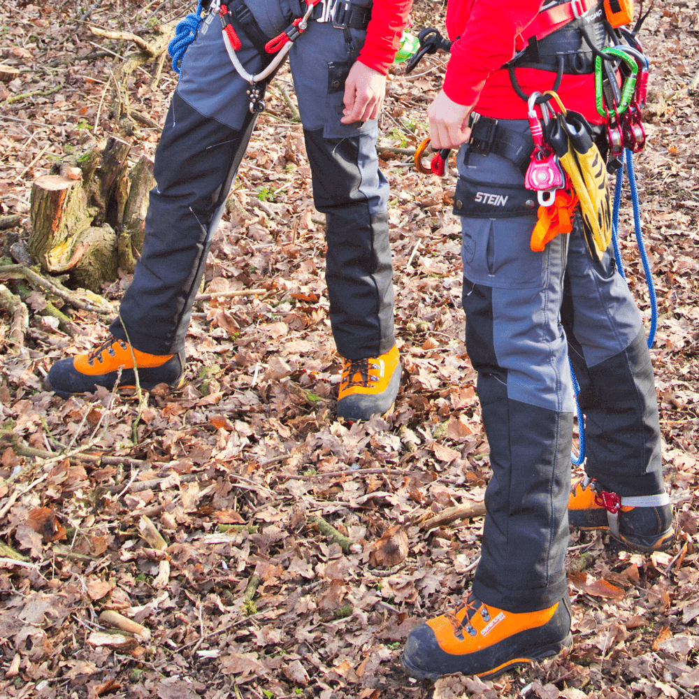 Close-up of STEIN Sentinel Chainsaw Trousers Type A worn by tree surgeons in a forest setting, showcasing their safety and durability.