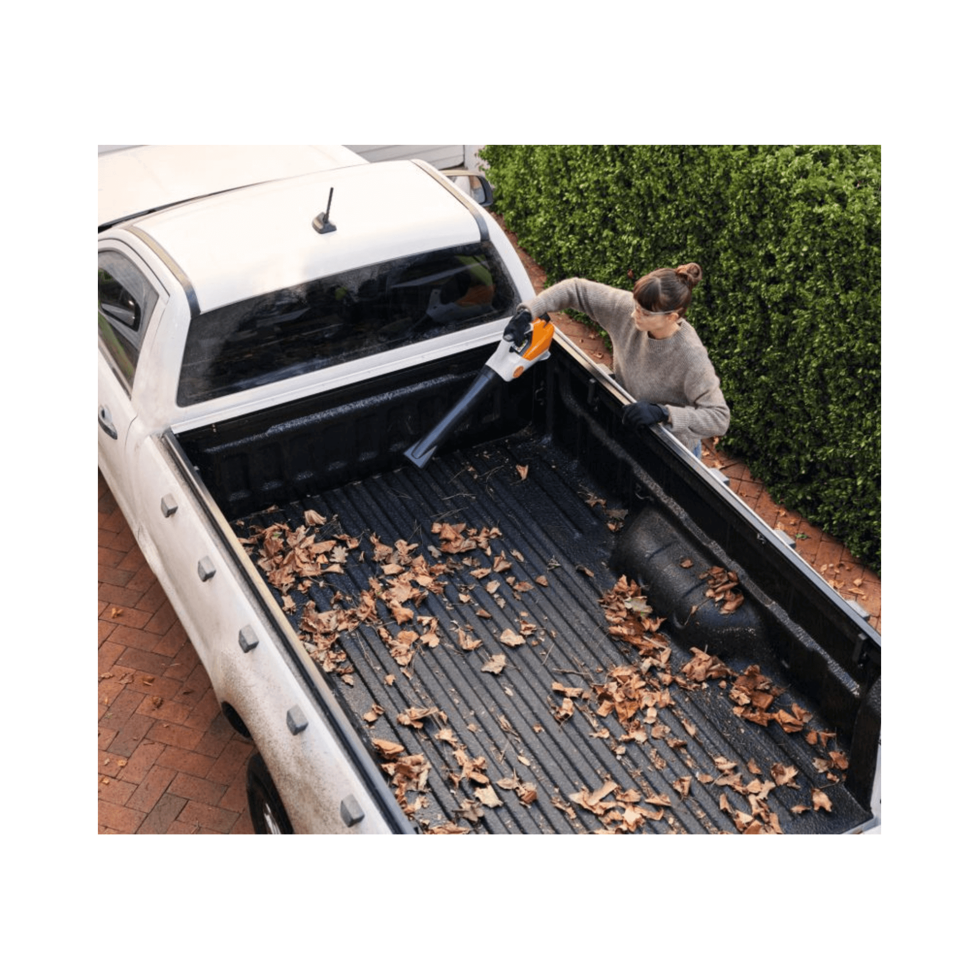 Person using the BGA 30 Cordless Leaf Blower to clear leaves from a truck bed.