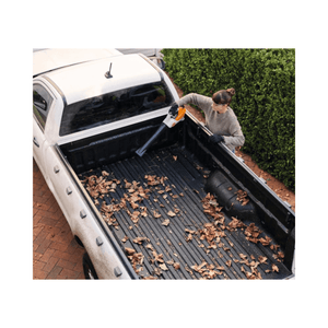 Person using the BGA 30 Cordless Leaf Blower to clear leaves from a truck bed.
