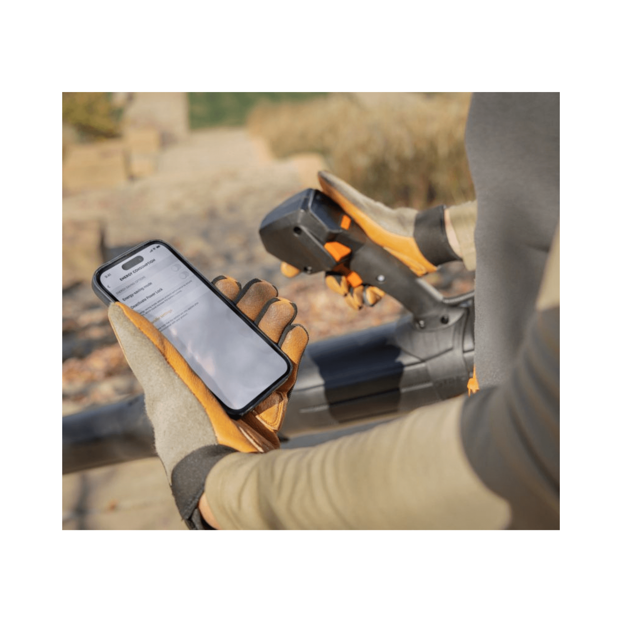 User operating the BRA 600 Cordless Backpack Leaf Blower while checking a smartphone outdoors.