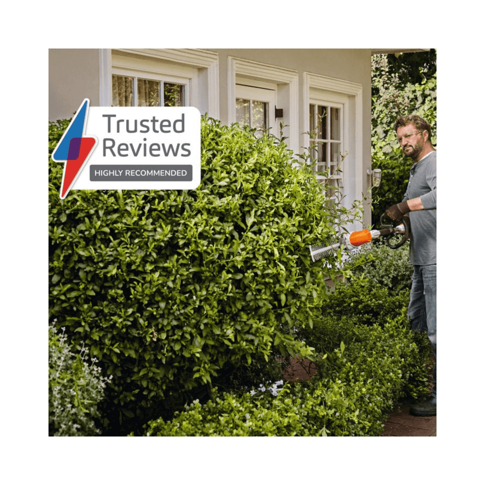 Man using HLA 56 Long Reach Cordless Hedge Trimmer to trim a hedge in a garden.