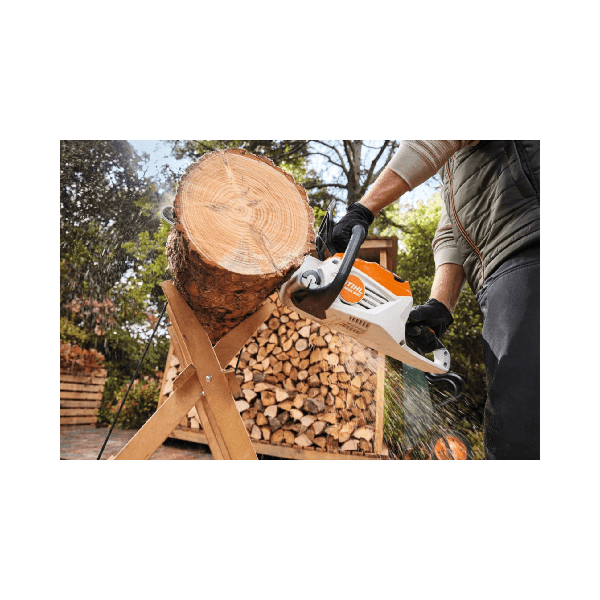 A user operates the STIHL MSA 80 C-B cordless chainsaw, cutting a log in a garden setting.