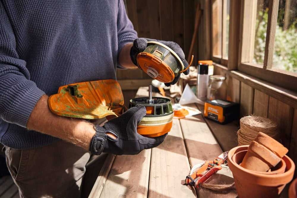 Person handling the spool of a STIHL FSA 70 R cordless strimmer in a garden shed.