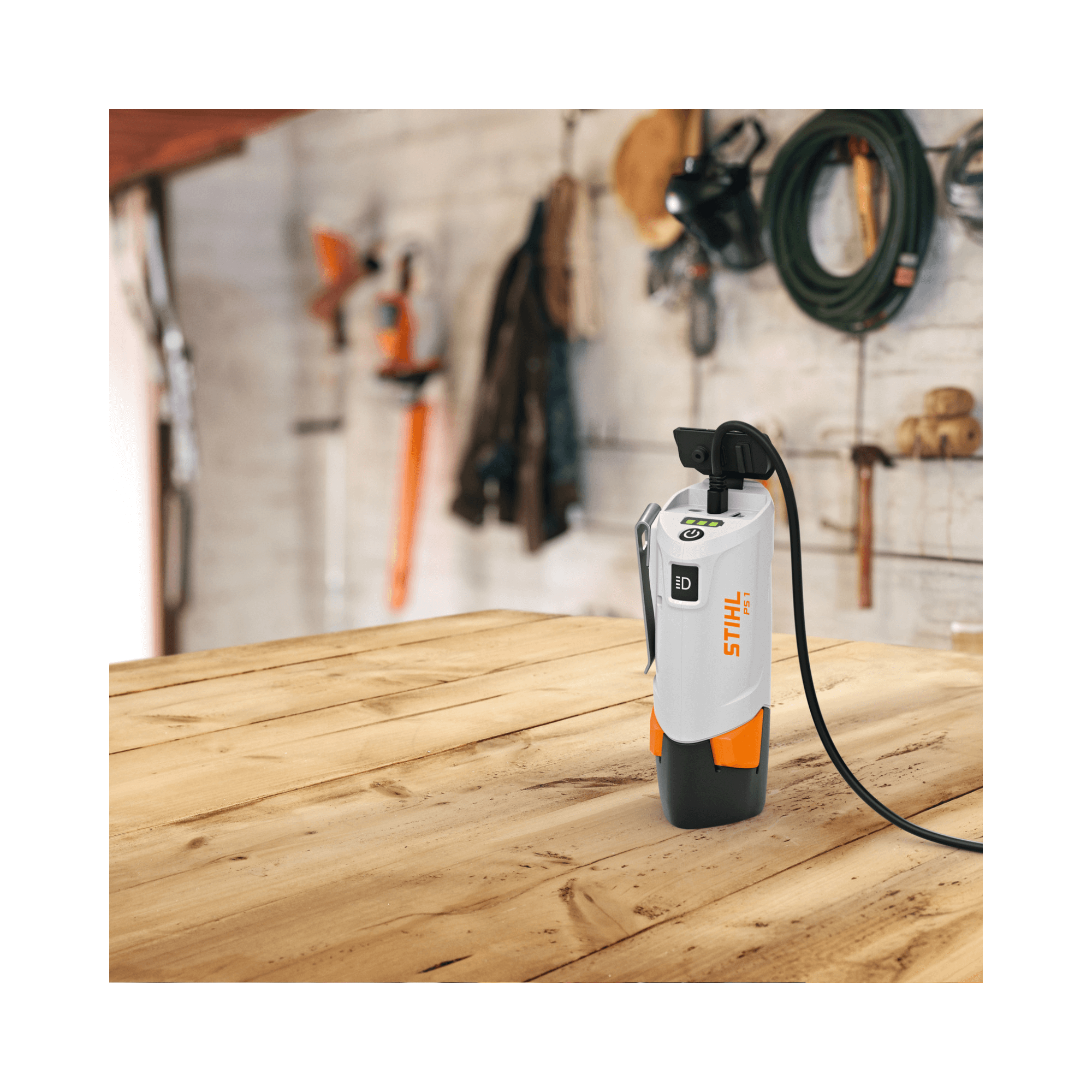 STIHL PS 1 Power Bank and Charger on a wooden table, ideal for tree surgeons and outdoor enthusiasts.