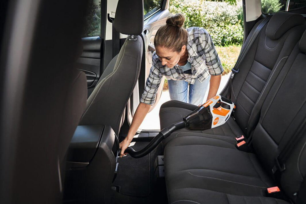 User cleaning car interior with STIHL SEA 20 Cordless Hand Vacuum, highlighting its compact design and efficiency.