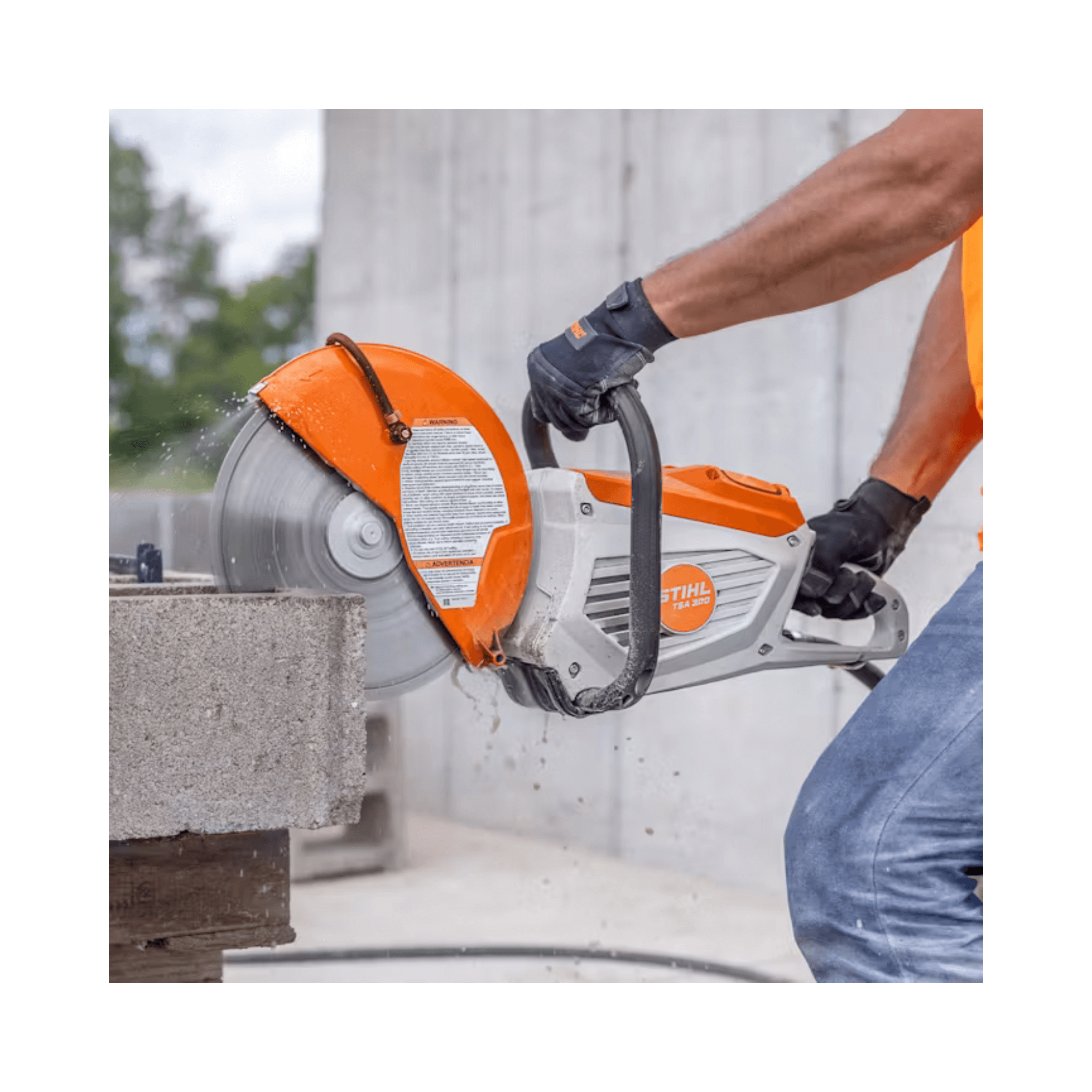 Person using a Stihl concrete saw to cut through a block with a blurred background