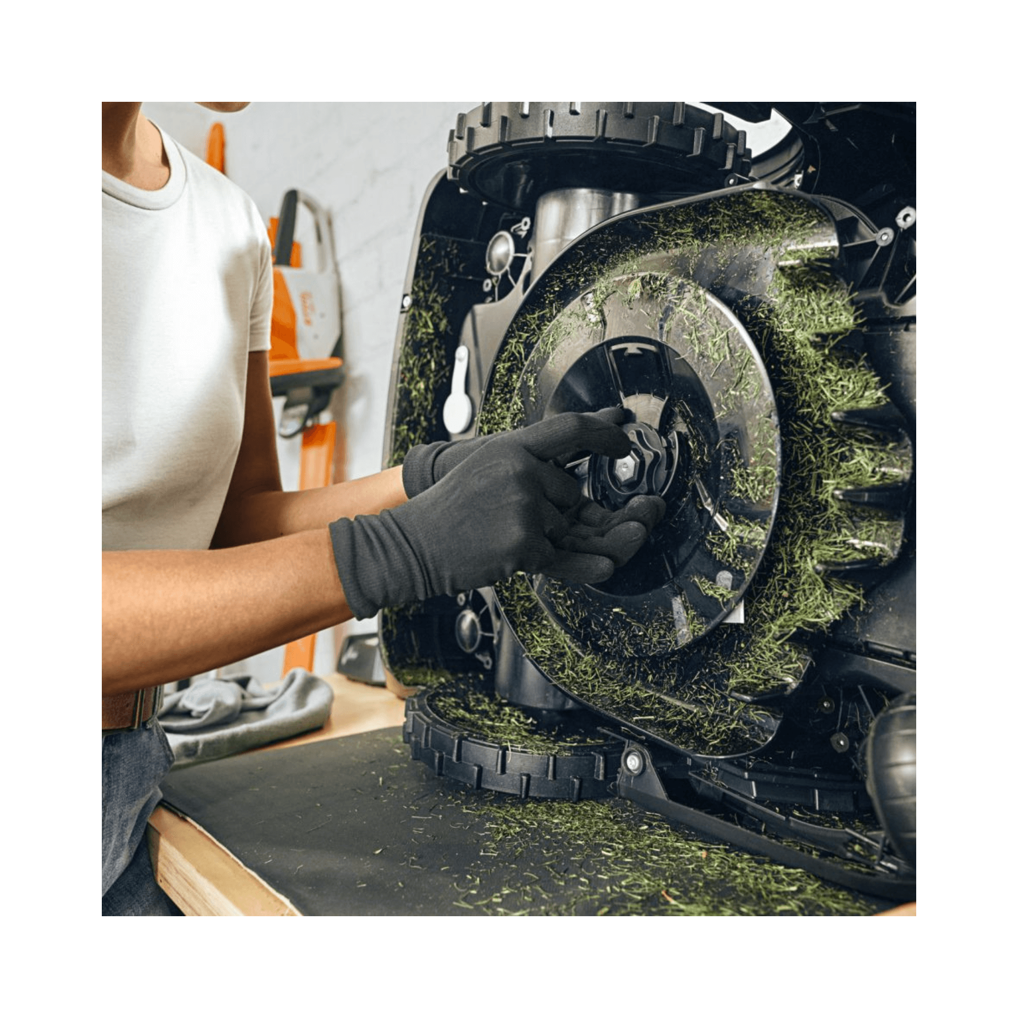 Person maintaining a robotic mower, showcasing STIHL iMOW DURO PLUS blades for enhanced lawn care.