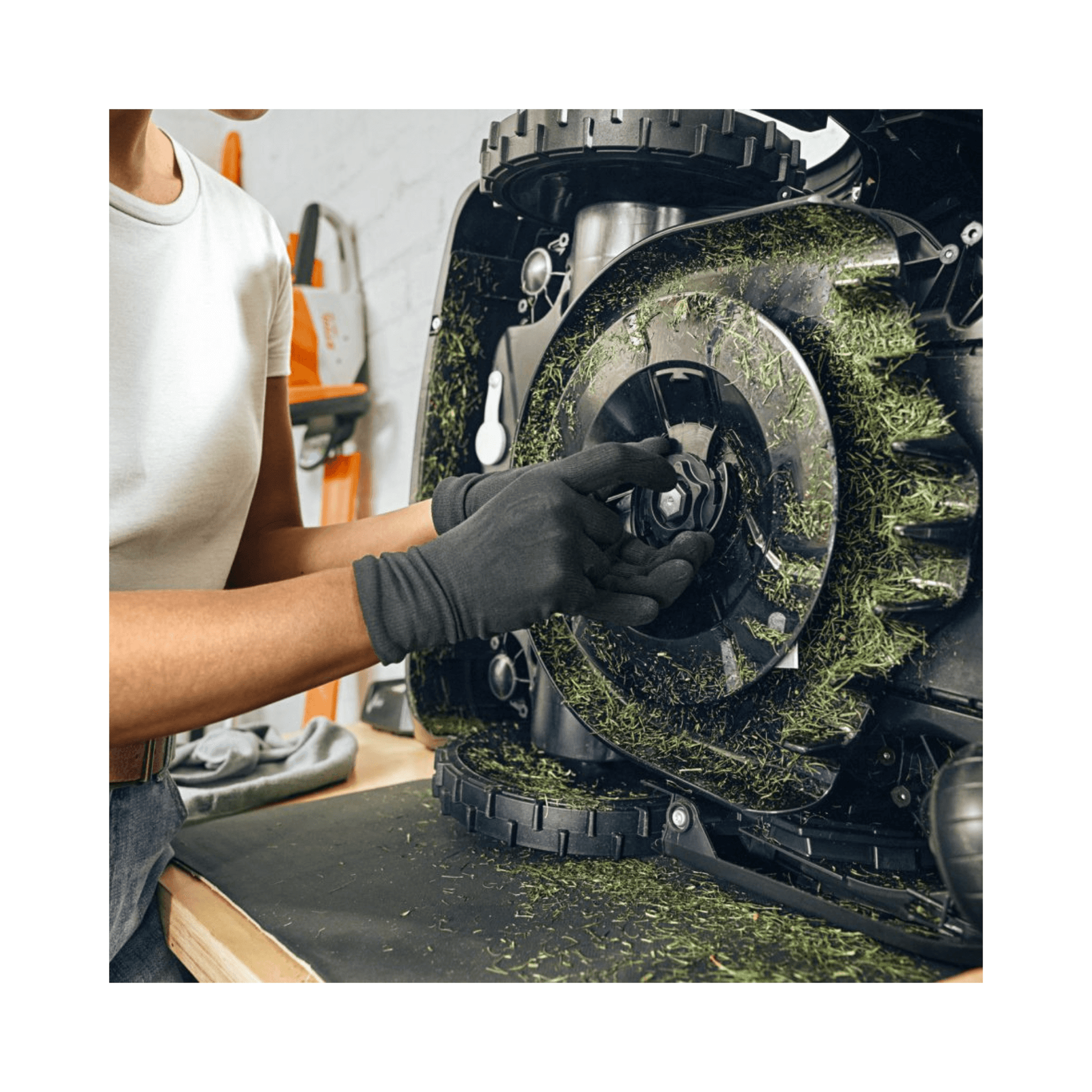 Person maintaining a robotic mower, showcasing STIHL iMOW DURO PLUS blades for enhanced lawn care.
