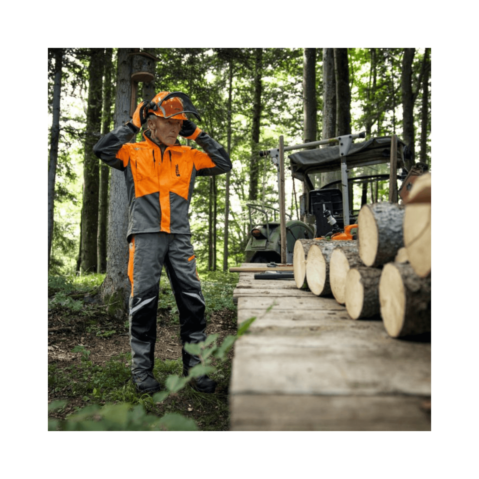 Tree surgeon wearing STIHL Function ERGO chainsaw trousers in forest, preparing to work with logs.