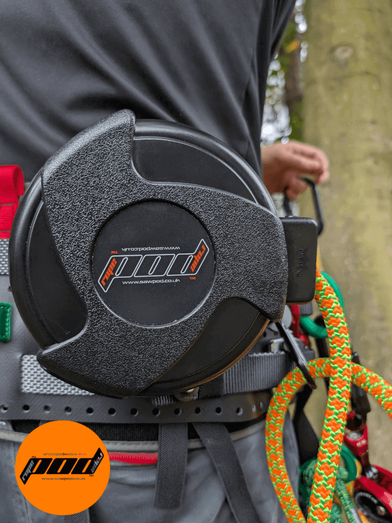 Close-up of a climbing ascender tool attached to a harness with colorful ropes, outdoors, showing safety gear in use.