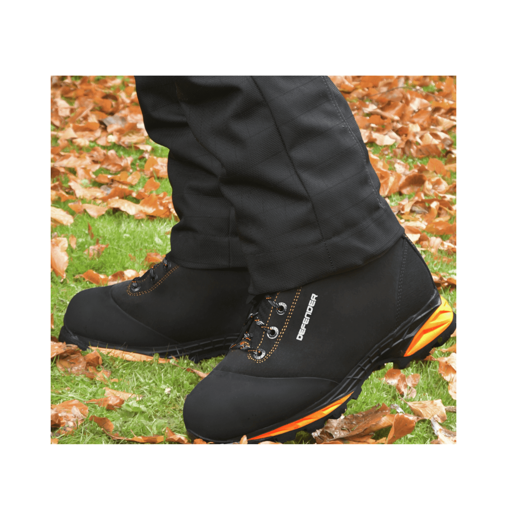 DEFENDER V2 Black Chainsaw Boots Class 2 shown on feet in an outdoor setting with fallen leaves.