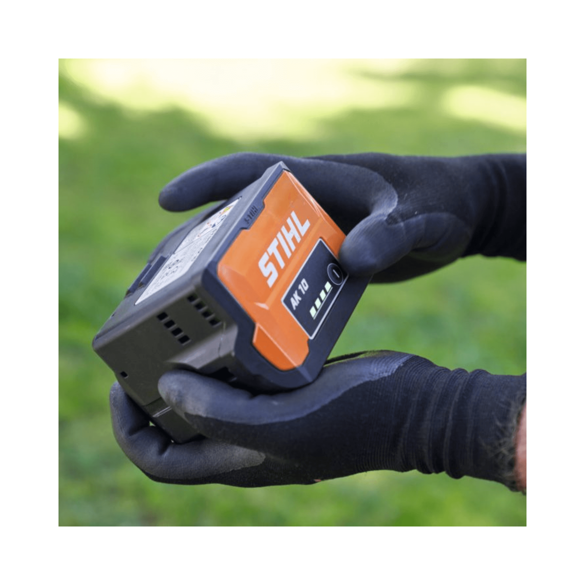 STIHL AK 10 Battery held in gloved hands, designed for efficient power in tree surgeon tools.