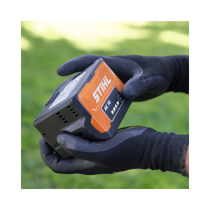 STIHL AK 10 Battery held in gloved hands, designed for efficient power in tree surgeon tools.