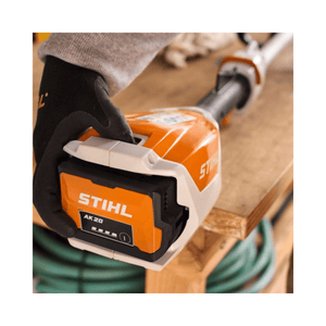Close-up of a user holding the STIHL AK 20 Battery, featuring its robust design for gardening tasks.
