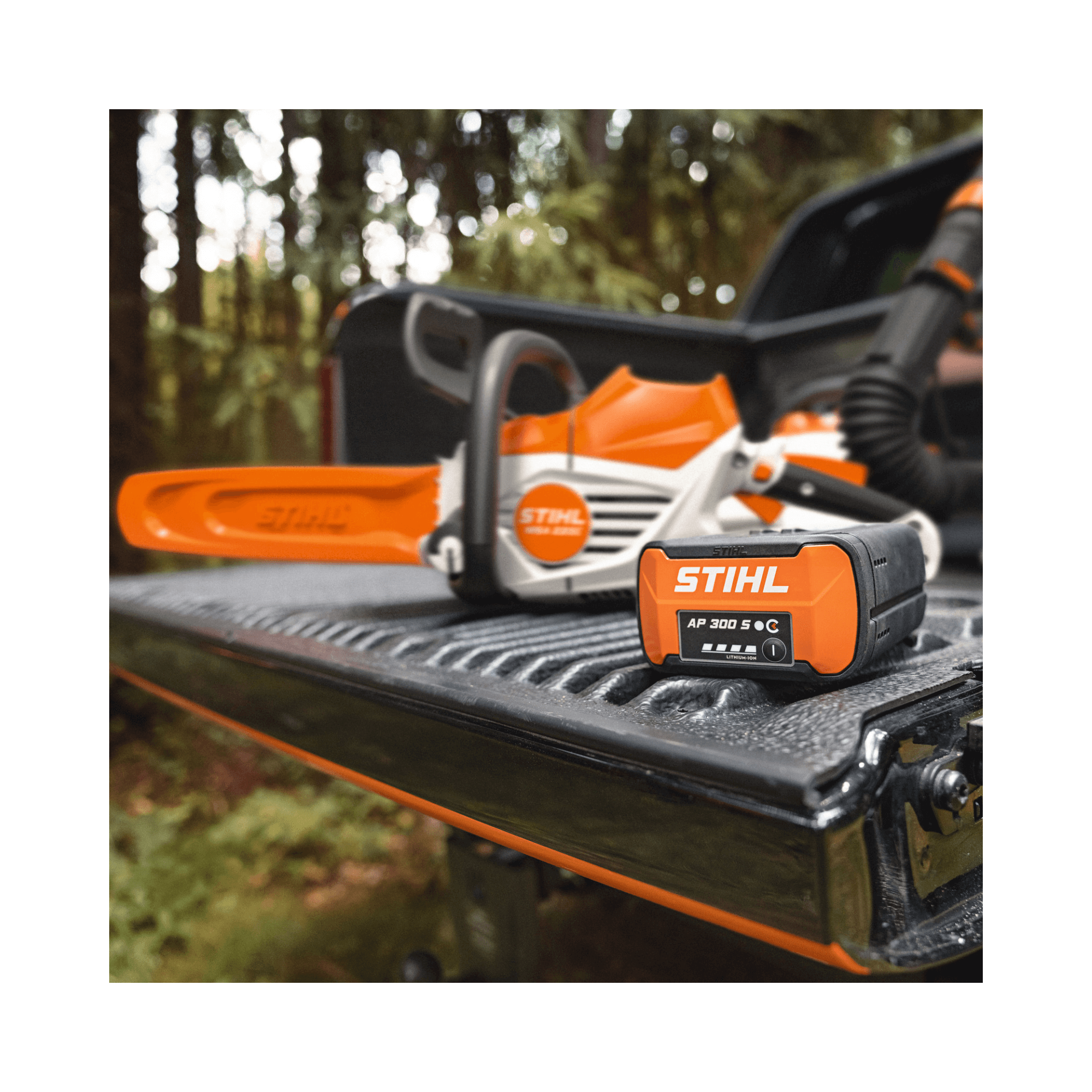 Stihl chainsaw and battery on a truck bed with a forest background