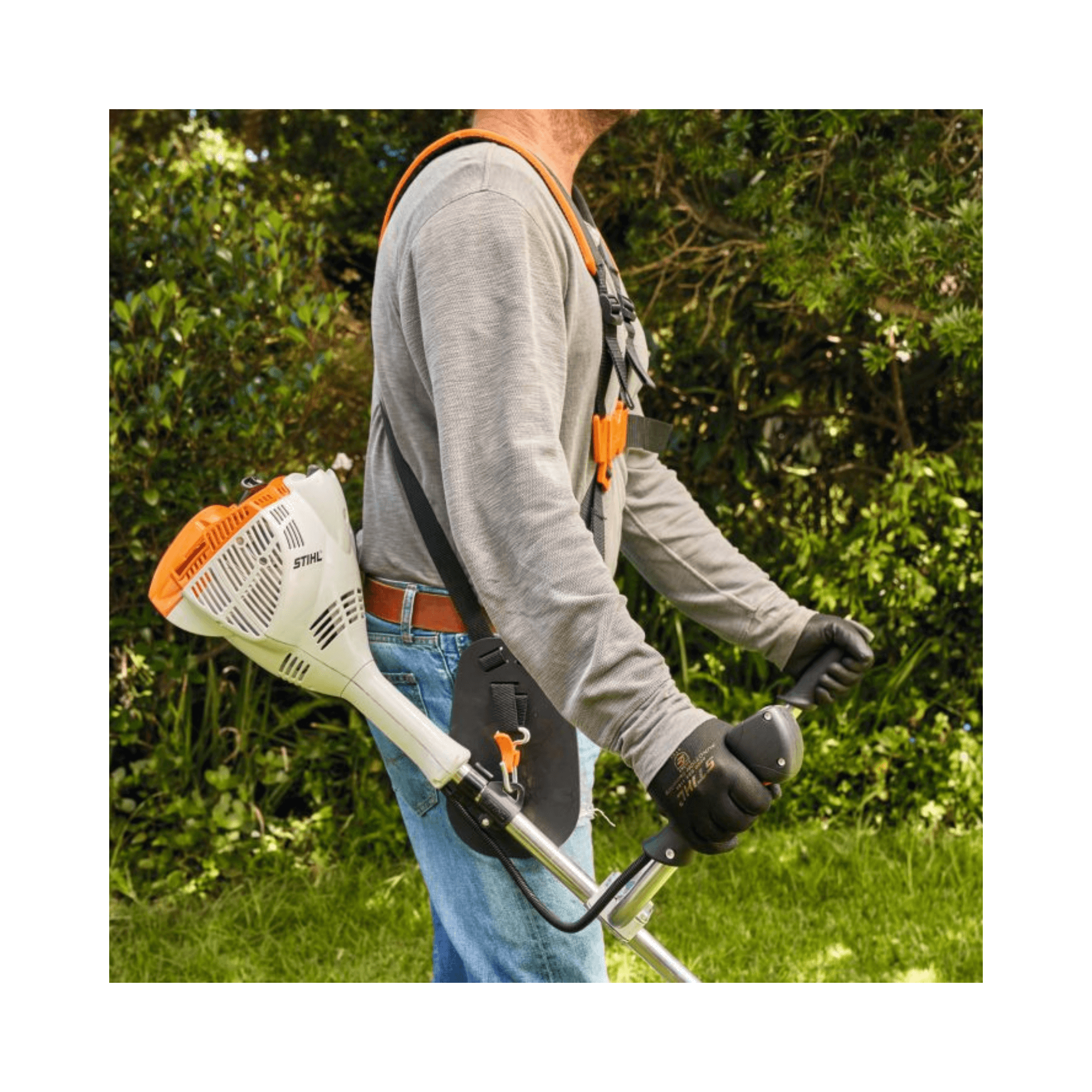 User operating the STIHL FS 56 C-E petrol brushcutter in a lush garden setting.