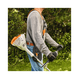 User operating the STIHL FS 56 C-E petrol brushcutter in a lush garden setting.