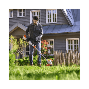 Man using a stihl grass strimemr in front of a house