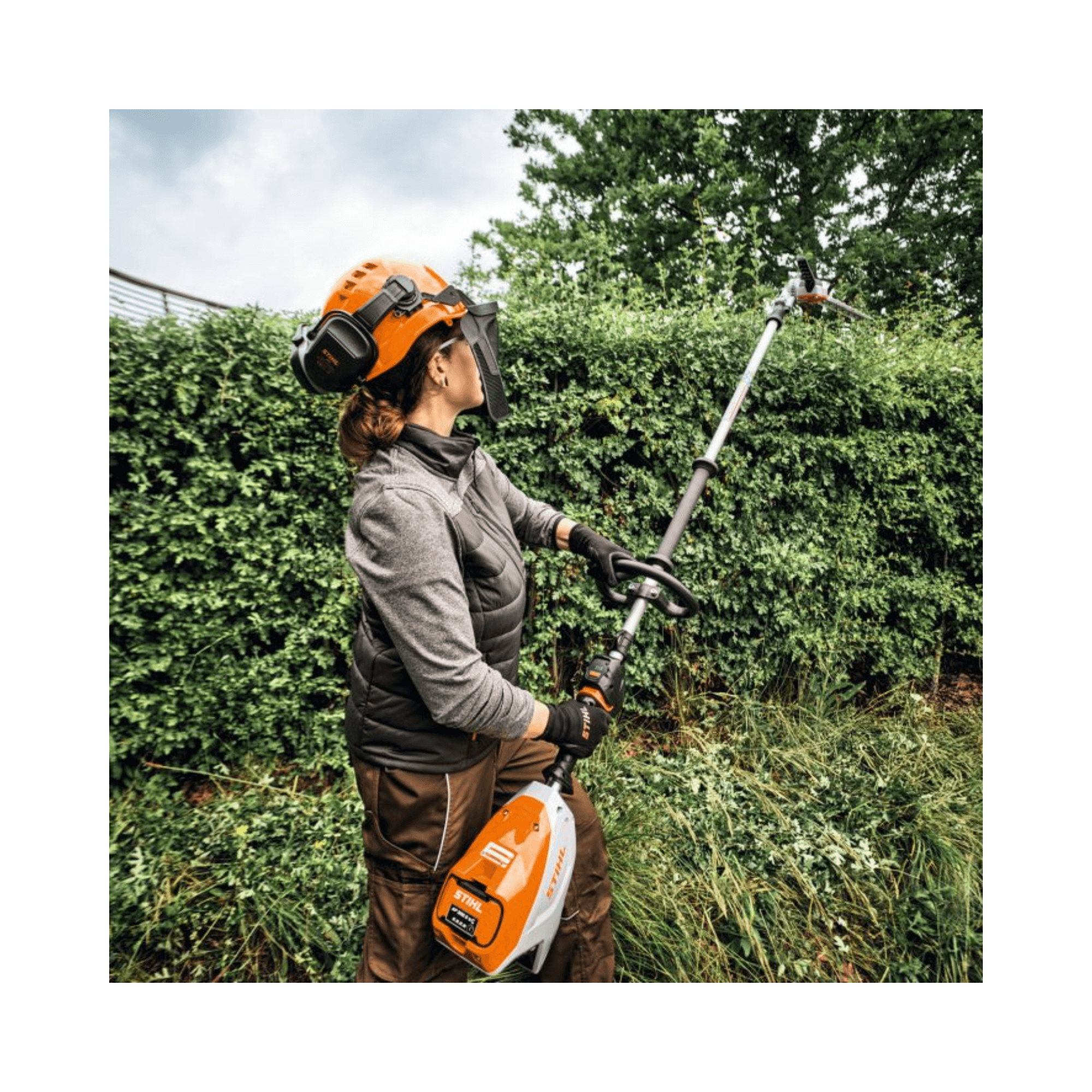 Woman using HLA 140 Cordless Long-Reach Hedge Trimmer for maintaining tall hedges.