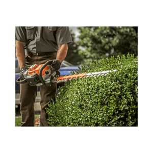 HS 82 RC-E Petrol Hedge Trimmer in action trimming a lush green hedge by a professional gardener.
