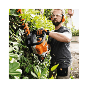 Man using STIHL HS 82 T Professional Petrol Hedge Trimmer for precision pruning in a garden.