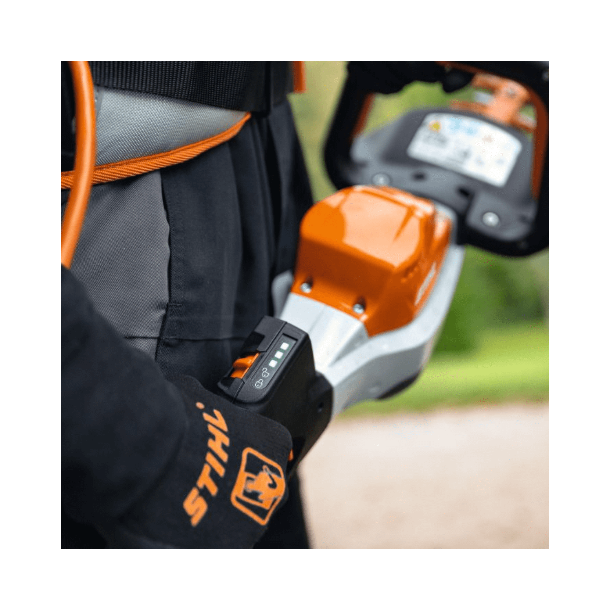 STIHL HSA 130 T Cordless Hedge Trimmer showing battery level indicator on professional gloves with detailed background.