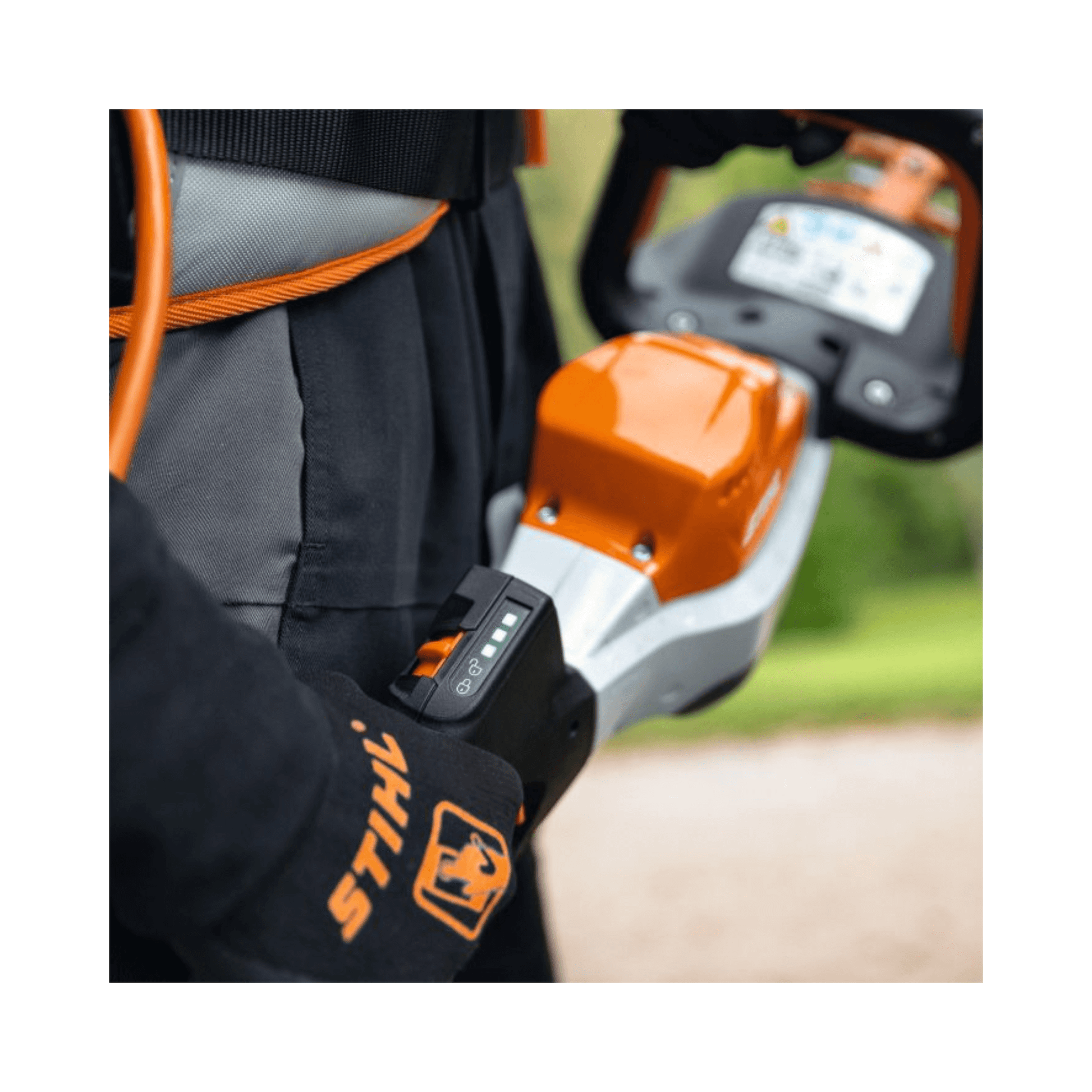 STIHL HSA 130 T Cordless Hedge Trimmer showing battery level indicator on professional gloves with detailed background.