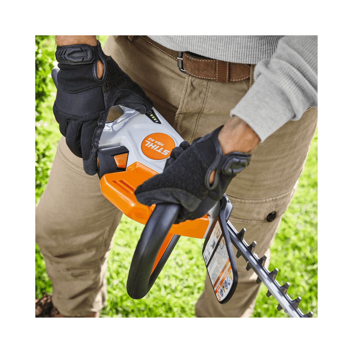 Close-up of hands holding the STIHL HSA 40 Cordless Hedge Trimmer 20" in a garden setting.
