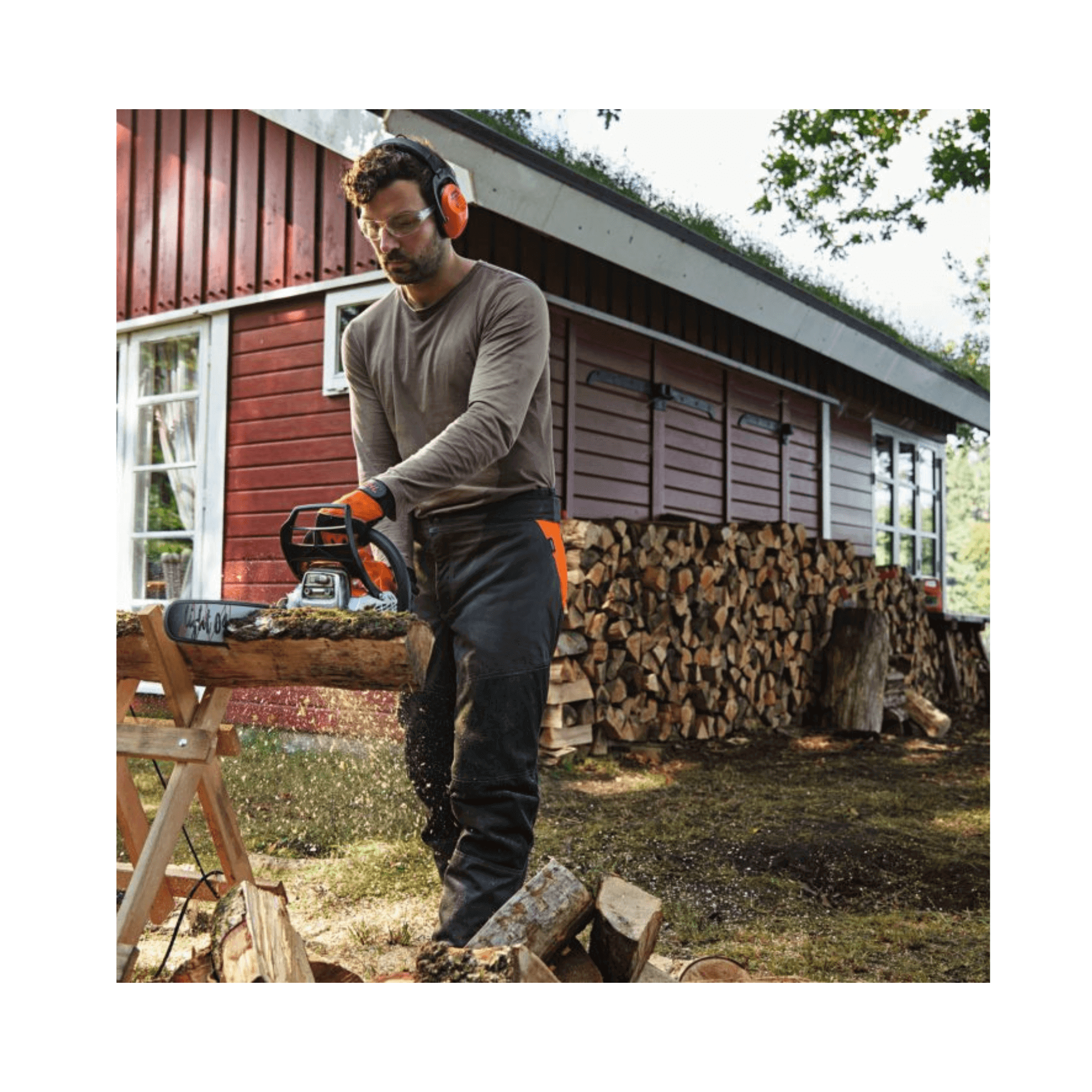 A man using a STIHL MS 212 C-BE petrol chainsaw to cut wood in a garden setting.