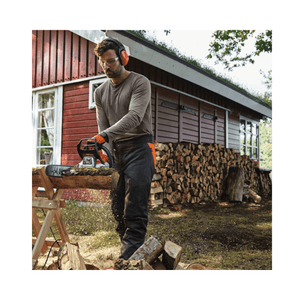 A man using a STIHL MS 212 C-BE petrol chainsaw to cut wood in a garden setting.