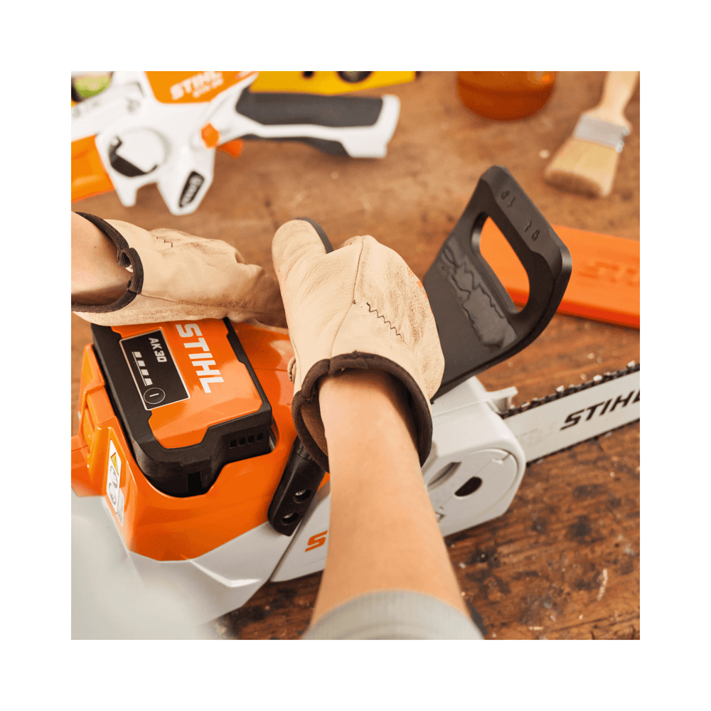 Hands wearing gloves adjusting the STIHL MSA 70 C-B cordless chainsaw, showcasing its lightweight design for tree surgeons.