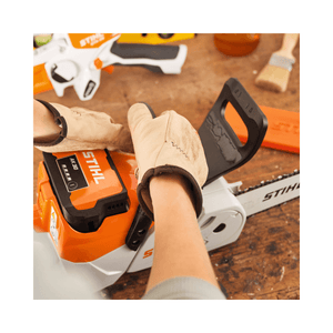Hands wearing gloves adjusting the STIHL MSA 70 C-B cordless chainsaw, showcasing its lightweight design for tree surgeons.