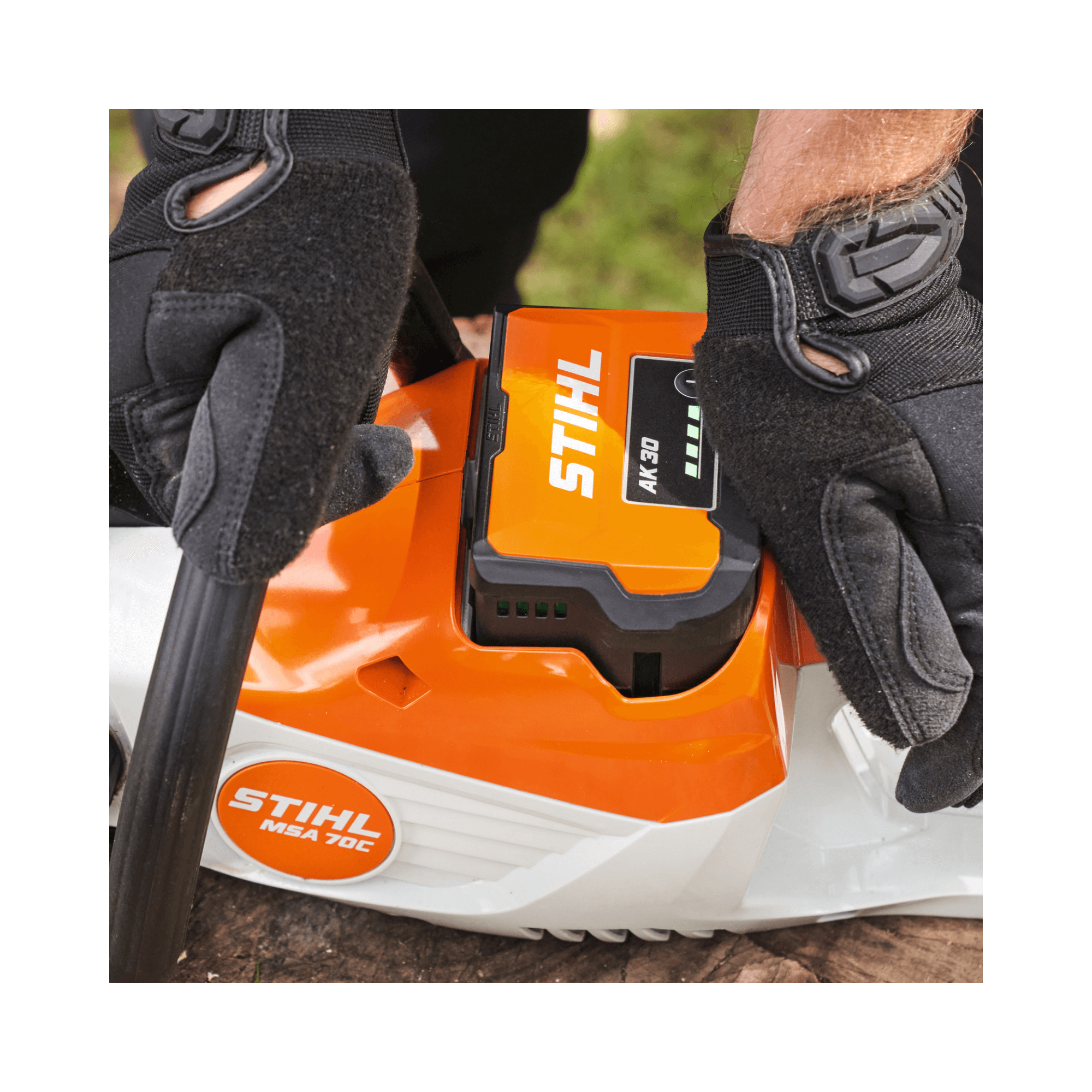Close-up of STIHL MSA 70 C-B cordless chainsaw battery connection, showcasing gloves for safety and precision.
