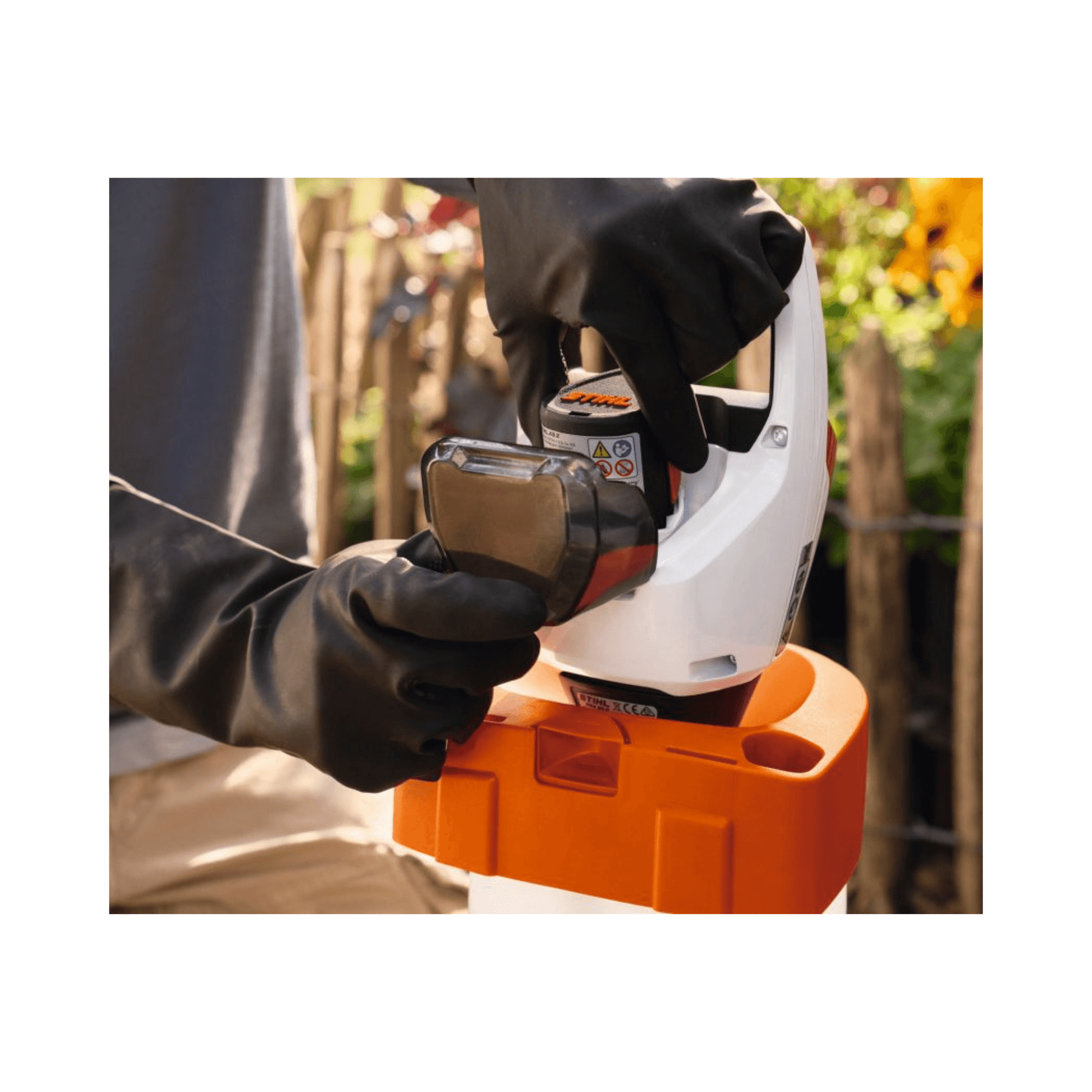 User operating the STIHL PKA 30 Cordless Pump Head with gloved hands in a garden setting.