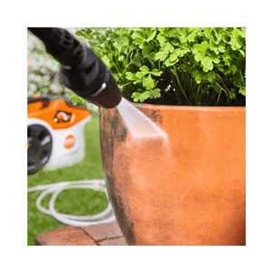 Cleaning a potted plant with the REA 60 PLUS Cordless Pressure Washer, showcasing its powerful spray.