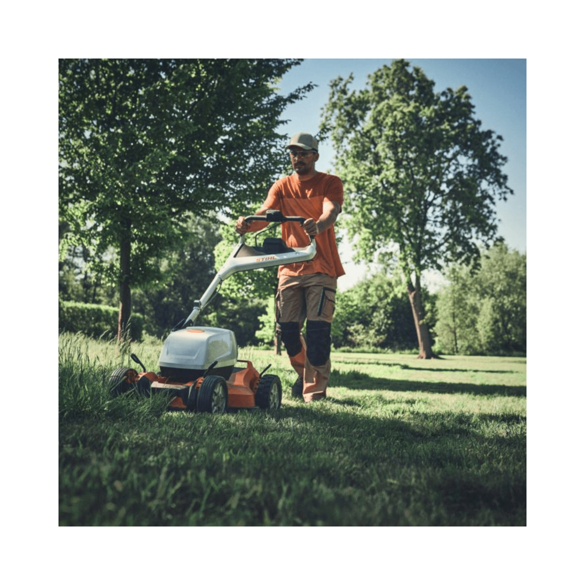 Man using RMA 7 RV Professional Cordless Mulching Lawnmower in a landscaped garden.